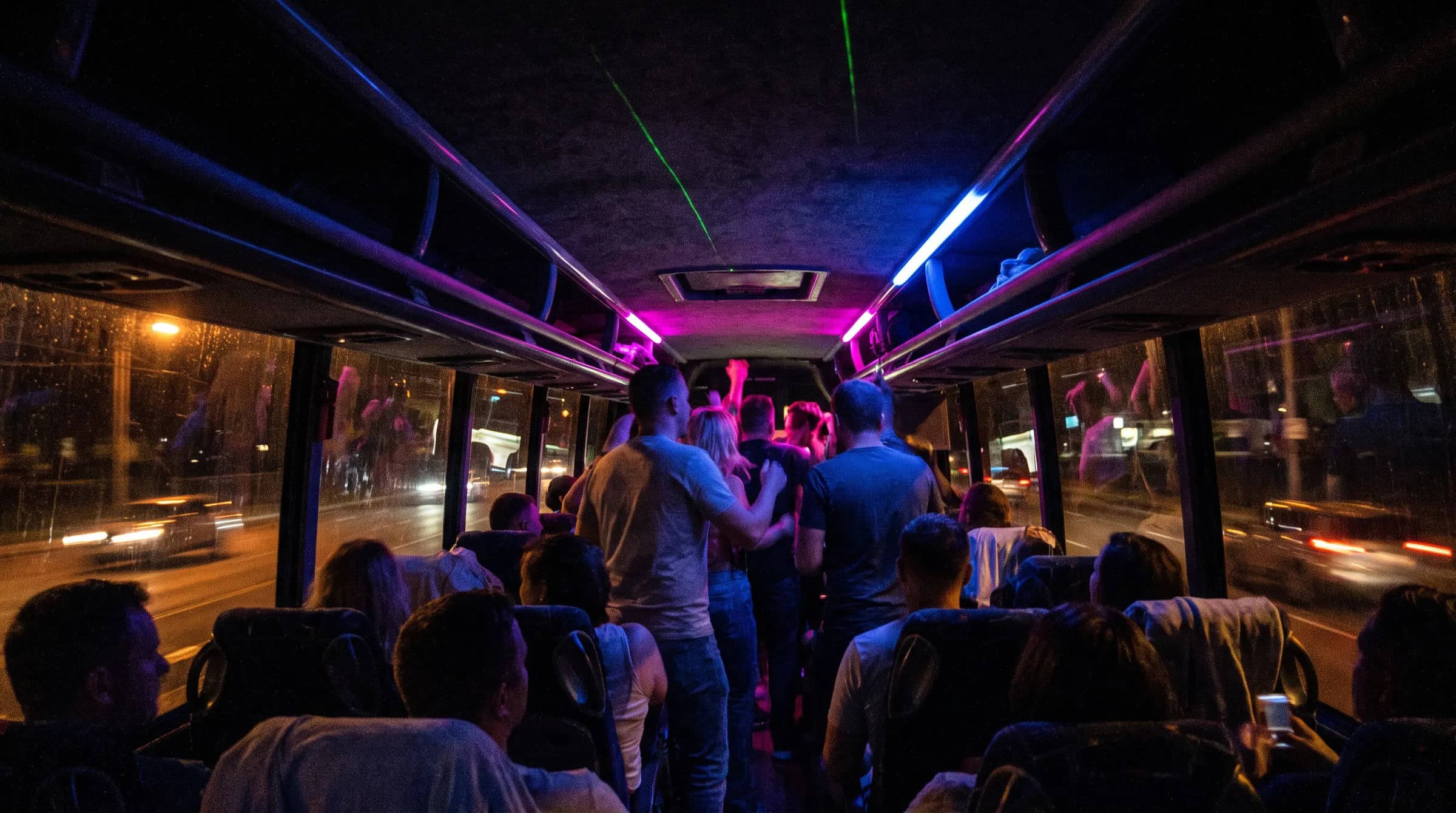 Binnen in een bus 's avonds: ledstrips in magenta en blauw langs het plafond, een groep staat te dansen